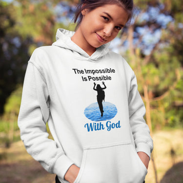 Gildan youth unisex hoodie with “Impossible Girl” design featuring a girl walking on water and uplifting message, Christian apparel made from soft preshrunk fleece, ideal for cooler weather and faith-forward style, teen girl in white hoodie